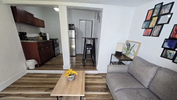A modern living room with a grey sofa, wooden coffee table, and a kitchen in the background. - Cozy & Central 1-Bedroom | Near the Design District (Miami)