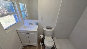 A bathroom with a toilet, sink, and shower. - Cozy & Central 1-Bedroom | Near the Design District (Miami)
