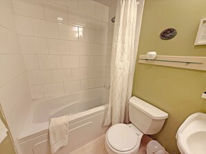 A bathroom with white tiles, a bathtub, a toilet, and a shower curtain. - Forestview Suite with Relaxing Tub & Private Bath - Rm 4 (Gabriola)