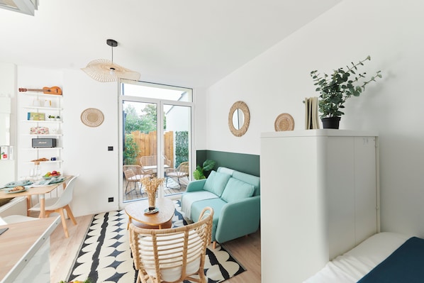 Un espace de vie moderne comprenant un coin repas, un canapé, un meuble et une plante en pot.
