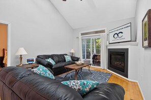 A living room with a fireplace, a sofa, a coffee table, and a lamp. - 323 Yacht Club's New Chapter | Peaceful Bay greenery retreat (Ocean Pines)