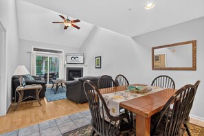 A modern living room with a dining area, a ceiling fan, a fireplace, and a large mirror. - 323 Yacht Club's New Chapter | Peaceful Bay greenery retreat (Ocean Pines)