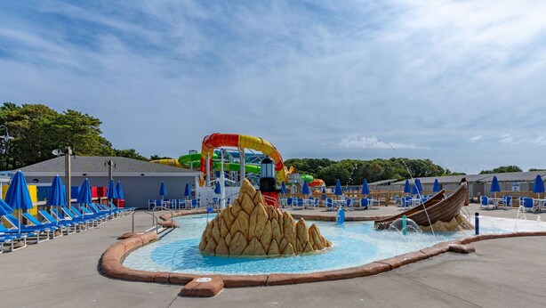A water park with slides, a pool, and lounge chairs. - Cozy Cape Cod 17A with Fire Pit Near Beaches (Yarmouth)