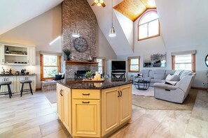 A spacious living area with a high ceiling, a kitchen island, and a large window providing natural light. - Serene Lake Pleasant House with Private Dock (Fremont)