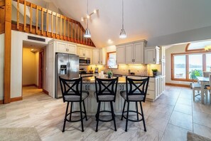 A spacious kitchen with a central island, bar stools, and pendant lighting. - Serene Lake Pleasant House with Private Dock (Fremont)