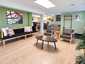 Un espacio lounge moderno con sofá, sillas y una mesita de centro.