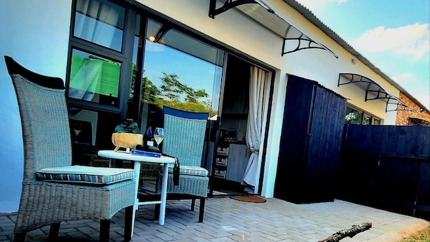 A patio with wicker chairs and a table, a sliding glass door, and a dark fence.