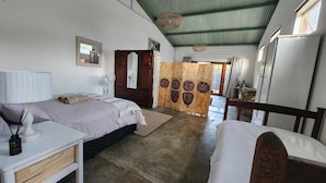 A room with two beds, a wooden wardrobe, a desk, and a chair.