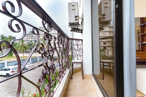 Ein Balkon mit schmiedeeisernem Geländer, Blick auf die Straße und ein Stuhl.