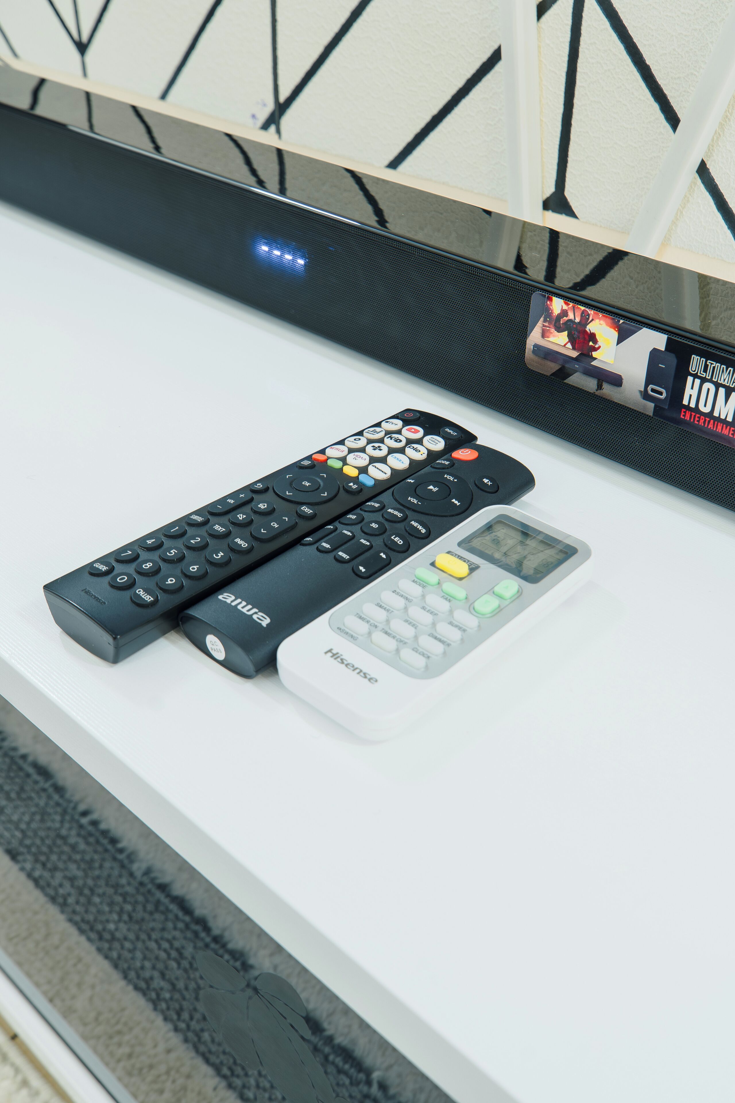 Une surface blanche avec trois télécommandes et un petit appareil électronique.