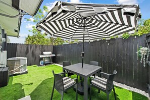 A patio with a table and chairs, a grill, and an umbrella. - 3-bedroom house in peaceful Boca Raton with cool AC breeze (Boca Raton)