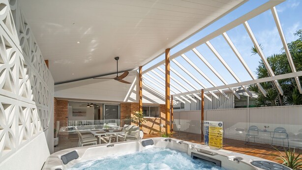 A hot tub with a ceiling fan, a patio area with chairs, and a view of the sky through a glass structure. - Coastal Comfort with a Private Spa Retreat (Margate)