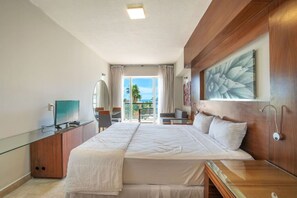 A hotel room with a bed, a TV, a desk, a chair, a balcony with a view, and a painting on the wall. - Estudio a 5 min de la playa en San José del Cabo (San José del Cabo)