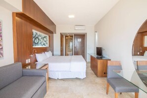 A hotel room with a bed, a sofa, a desk with a TV, and a bathroom visible through an open door. - Estudio a 5 min de la playa en San José del Cabo (San José del Cabo)