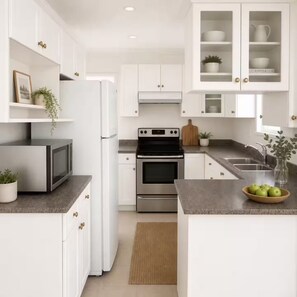 A modern kitchen with white cabinets, stainless steel appliances, and a granite countertop.