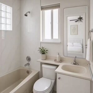 A bathroom with a bathtub, toilet, sink, and a window with blinds. - Sweet suite in Sophia’s home 201 (Vancouver)
