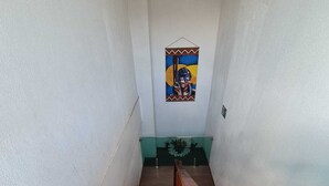 Una escalera de madera con barandilla que conduce a una habitación con pared verde y un adorno en la pared.