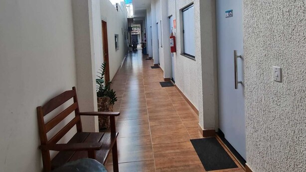 Un largo pasillo con un banco, puertas y suelo de baldosas.