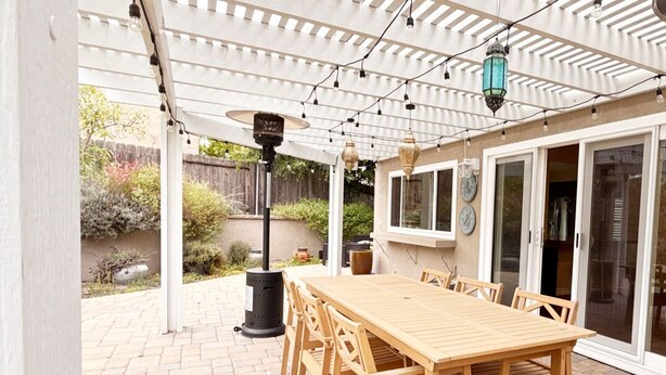 A covered patio with a wooden table and chairs, string lights, and a pergola. - UC Gem with Beautiful Yard (San Diego)