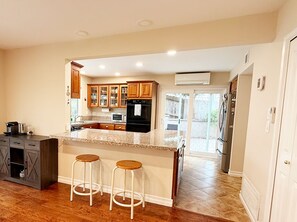 A kitchen with wooden cabinets, a granite countertop, and a central island with stools. - UC Gem with Beautiful Yard (San Diego)