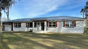 Ein eingeschossiges Haus mit Garage, einer Veranda und einem Metalldach.