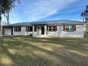 Ein eingeschossiges Haus mit Garage, einer Veranda und einem Metalldach.