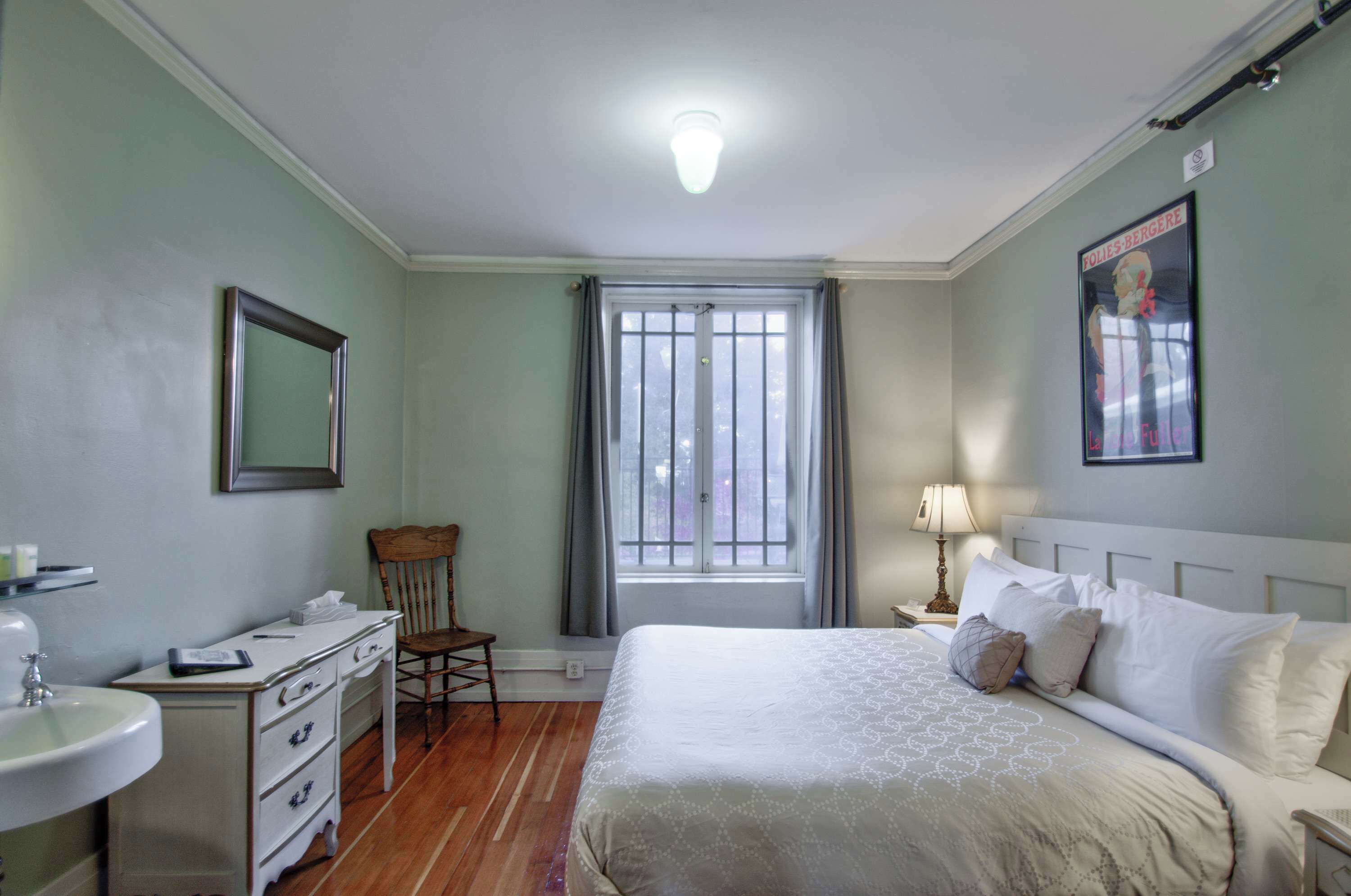 Ein Schlafzimmer mit Bett, Schreibtisch, Stuhl, Fenster und einem Poster an der Wand.