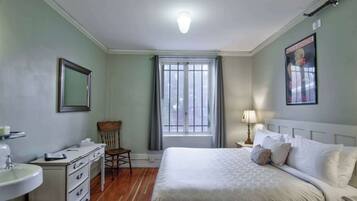 Ein Schlafzimmer mit Bett, Schreibtisch, Stuhl, Fenster und einem Poster an der Wand.