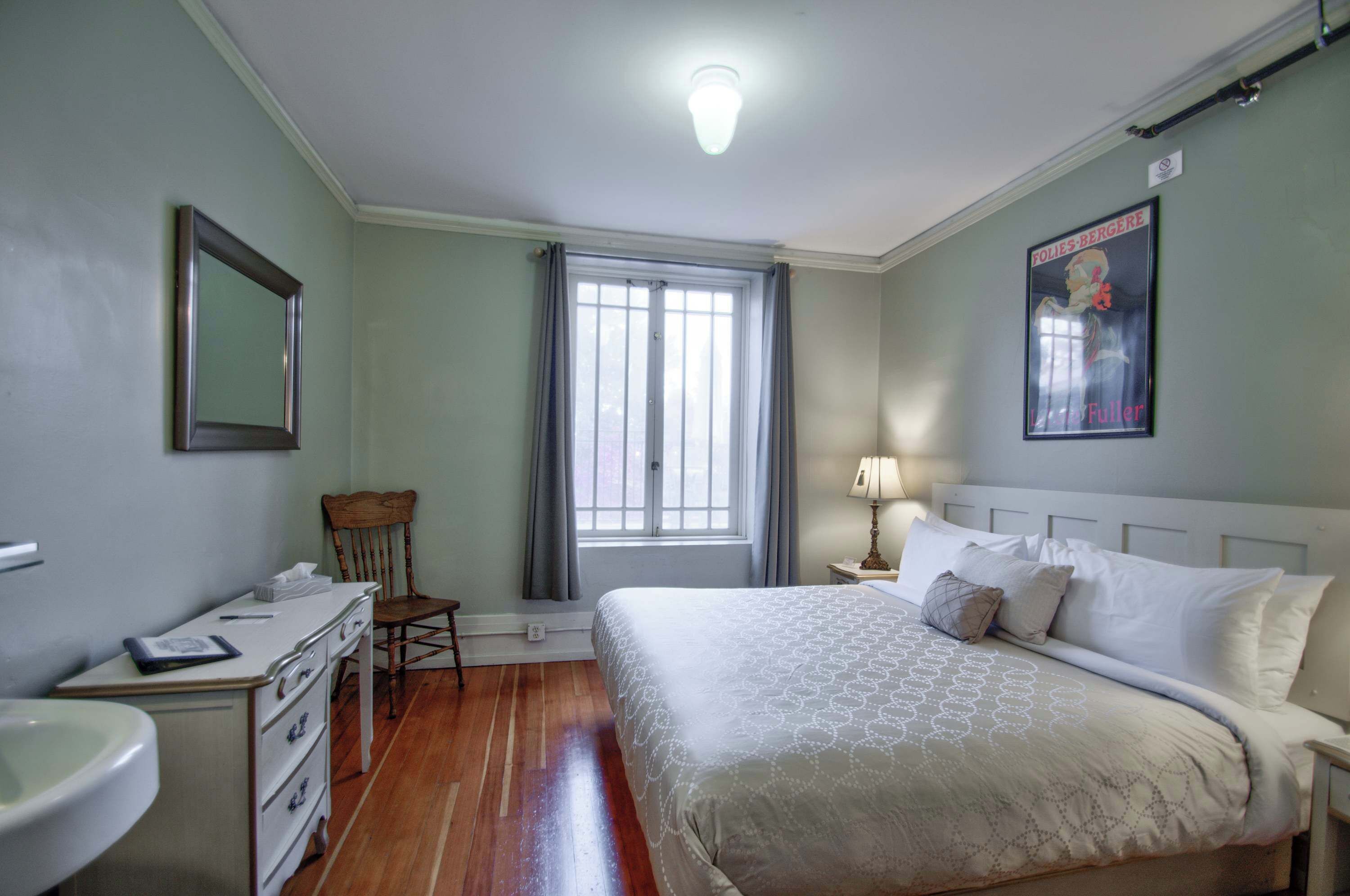 Une chambre à coucher avec un lit, une chaise, un bureau et une fenêtre.