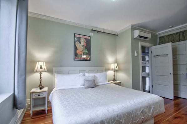 Een slaapkamer met een bed, twee nachtkastjes met lampen, een poster aan de muur en een kledingkast.