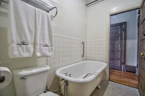 Une salle de bain comprenant des toilettes, une baignoire et un espace douche.