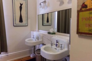 A bathroom with two sinks, a mirror, and a framed artwork on the wall.