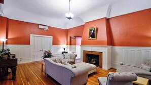 A living room with a fireplace, a sofa, a chair, and a piano. - The Peak at Centralia Square | Room 308 (Centralia)