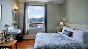 A hotel room with a bed, a window with curtains, a sink, and a chair. - The Peak at Centralia Square | Room 308 (Centralia)