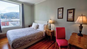 Una habitación de hotel con cama, una silla, una mesa y una ventana que ofrece vista a la ciudad.