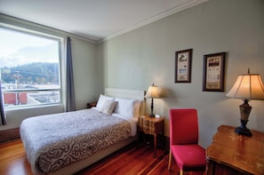 Una habitación de hotel con cama, una silla, una mesa y una ventana que ofrece vista a la ciudad.