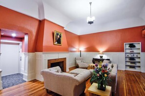 Una sala de estar con chimenea, un sofá, una mesa con un florero y una estantería.