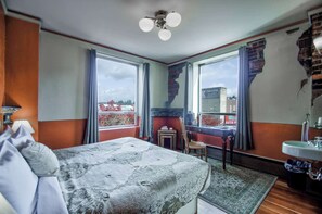 Een slaapkamer met een bed, een stoel, een raam, een open haard en uitzicht op de omgeving.