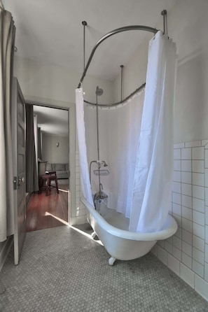 Un baño con una bañera independiente, cortina de ducha y suelo de baldosas.