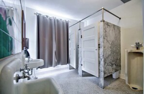 A bathroom with a sink, shower curtain, and a marble wall.