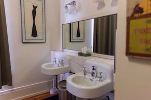 A bathroom with two sinks, a mirror, and a framed artwork on the wall.