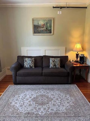 A living room with a dark brown sofa, patterned rug, and a lamp on a side table.