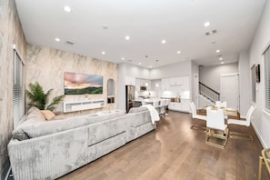 A modern living room with a sofa, TV, and dining area. - Welcome to Freeman’s House! 
Heart of DTWN HTX ! (Houston)