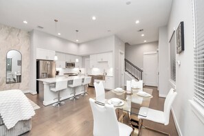A modern kitchen with white cabinets, a stainless steel refrigerator, and a central island with bar stools. - Welcome to Freeman’s House! 
Heart of DTWN HTX ! (Houston)