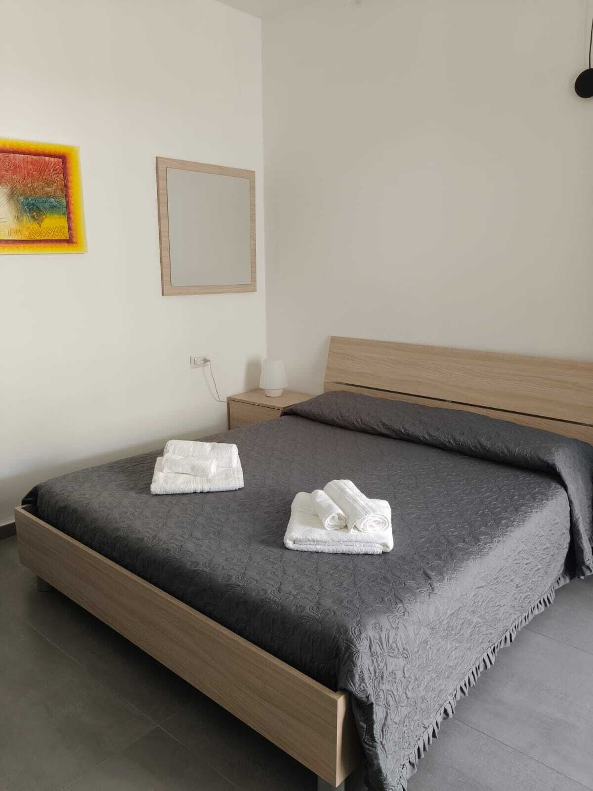 Une chambre à coucher avec un lit, une table de chevet, une lampe, un miroir et un tableau accroché au mur.