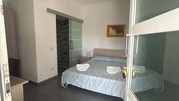 A modern bedroom with a bed, a wardrobe, a desk, and a bathroom.