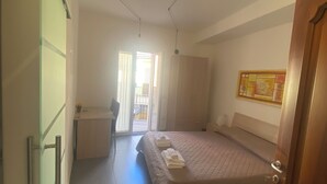 A bedroom with a bed, a desk, and a door. - Old Town Room 1 (Tortolì)