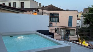 A rooftop swimming pool with a lounge area, surrounded by buildings. - Old Town Room 1 (Tortolì)