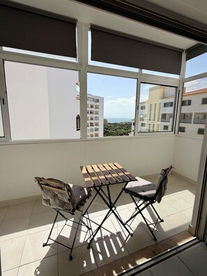 A balcony with a wooden table and chairs, a view of buildings, and a clear sky. - Azul,: A cozy apartment just a few steps from Praia da Rocha (Portimão)