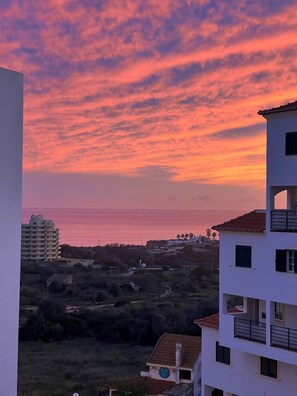 A coastal view with a sunset, buildings, and a clear sky. - Azul,: A cozy apartment just a few steps from Praia da Rocha (Portimão)